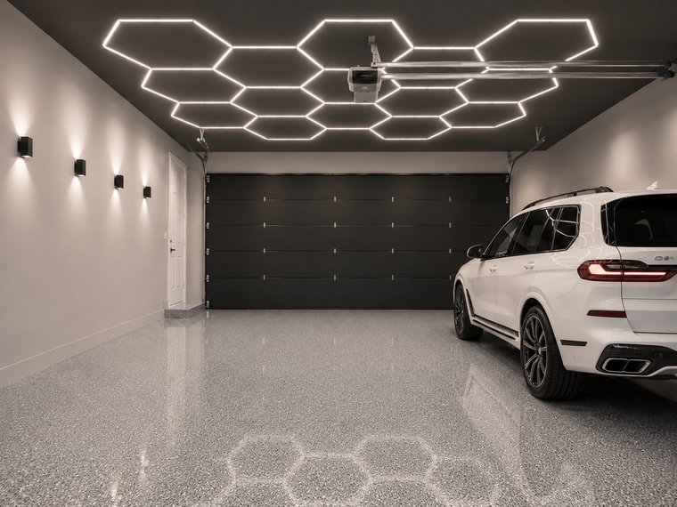 Fully renovated garage with honeycomb ceiling lighting and parked SUV